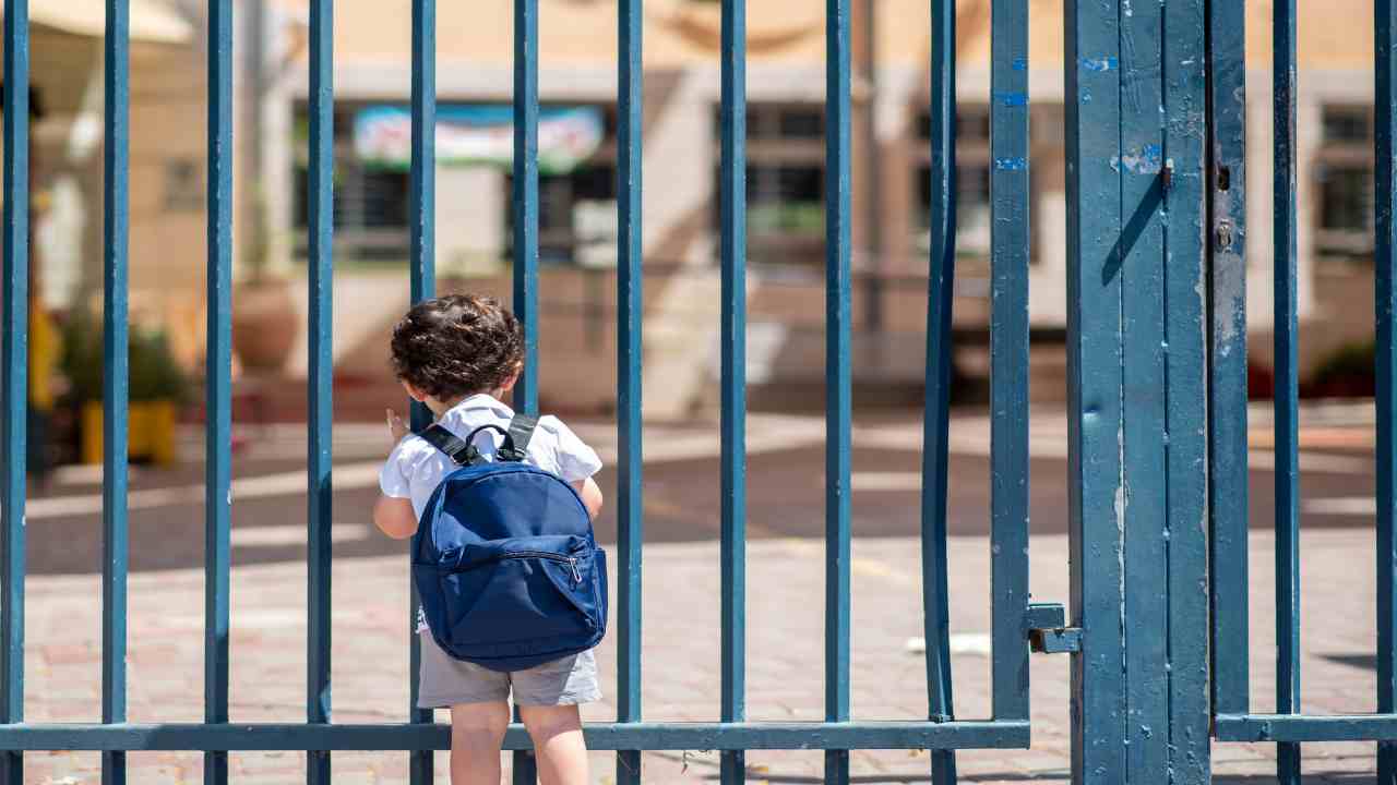 Bambino davanti alla scuola chiusa